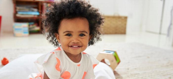 A baby smiling at the camera at nursery