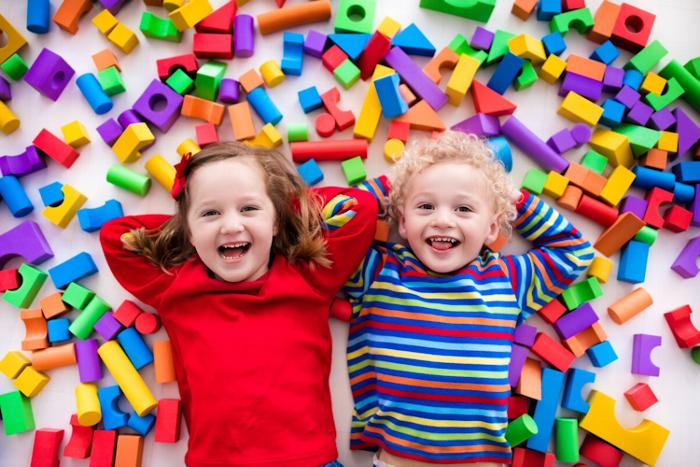 Children smiling at camera with building blocks in the background